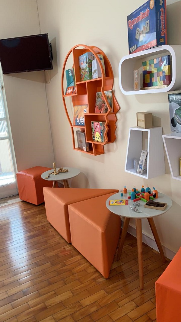 Imagem interna da unidade Pedro Leopoldo (MG), decoração laranja com estante e livros laranja 