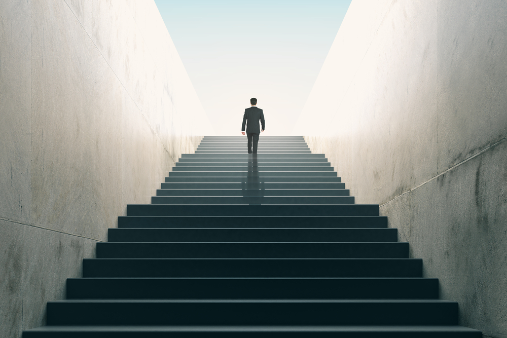 Homem de negócios subindo escadas. A ideia é ilustrar a importância de algumas habilidades para garantir sucesso.